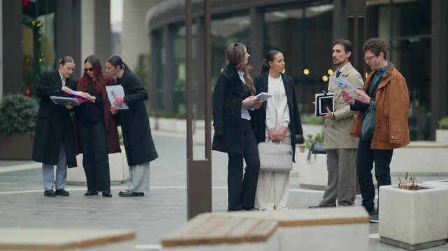 Diverse business professionals engage in collaborative discussions outdoors in a contemporary urban setting.