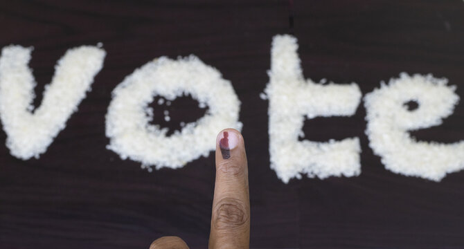 Vote text formation in the rice crop on the wooden cardboard to indicate the right to vote with fingure tip with ink mark denotes after casting the vote