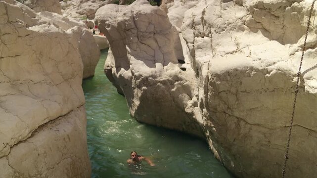 Slow Motion Male Tourist Swimming in Wadi Bani Khalid, Cinematic Emerald Water and Limestone Canyon in Oman