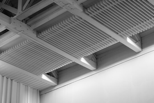 White wooden ceiling with exposed beams and slatted panels creates strong geometric lines, minimal modern texture. High-contrast interior architecture emphasizes pattern, structure, industrial style