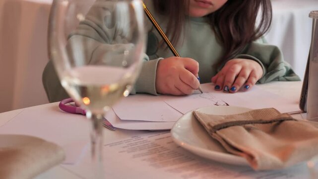 An unknown child draws with a pencil, close-up of his hands.