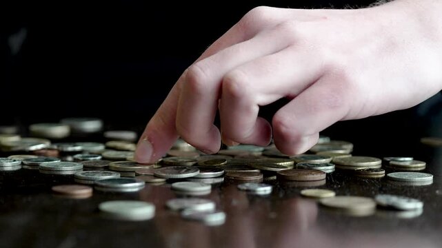 Person sorting through many coins on a table, searching for a specific one

