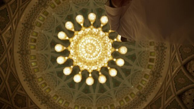 Straight-Up Shot of Grand Sultan Qaboos Mosque Chandelier with Tourist Walking Into View, Cinematic Interior in Muscat