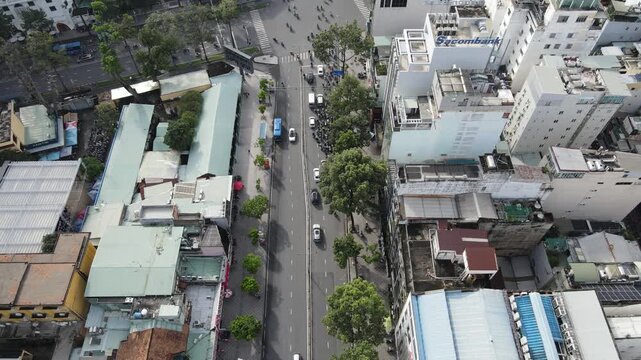 Aerial view of busy city traffic at an intersection with motorbikes and cars among dense urban buildings in Ho Chi Minh City, Ho Chi Minh, Vietnam.