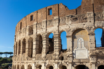 Fototapeta premium Famous Coliseum in Rome. Colosseum, or Coliseum. Part of the wall of an antique stone structure with arches. Italy, Europe. Famous touristic place in the world, Europe. Beautiful blue sky background.