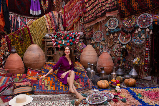 a beautiful girl in dress in a traditional turkish interior with many carpets on the wall