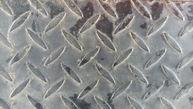 Worn Metal Diamond Plate Industrial Texture. Close-up of scratched metal plate with diamond tread pattern, showing industrial wear and use