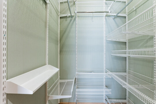 Neat Organized Closet. Minimalist Storage With Adjustable Shelves. Bright White Metal Racks With Tidy Finish. Walkin Closet Featuring Clean Paint And Versatile Shelving Solutions