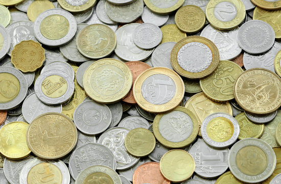 Pile of global currencies, various coin types visible up close. Different nations money together