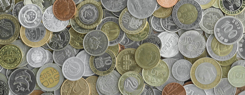 Top view of assorted coins, numerous world currencies together. Shiny metal pieces in mound