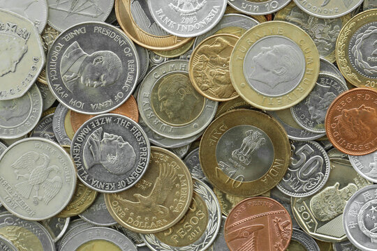 Top view of assorted coins, numerous world currencies together. Shiny metal pieces in mound