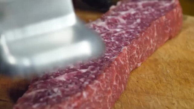 A close-up shot of a premium raw Wagyu Denver steak (Zabuton cut) showcasing its intricate intramuscular fat and rich red color, resting on a rustic wooden cutting board in a professional kitchen sett