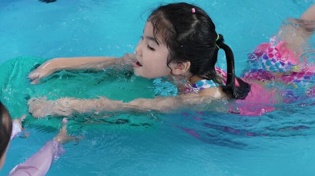 slow motion of happy preschool child girl playing together with her sister in outdoor portable swimming pool in backyard at home