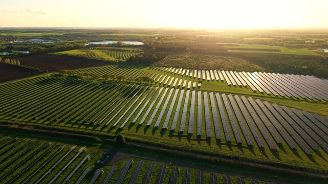 Aerial view of Tiln Battery Energy Storage System with solar panels in rows across green fields at sunset in Retford, England, United Kingdom.