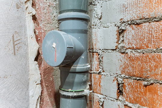 Closeup Of Pipe Connection With Sealant And Grout Texture Details. Inspection Of Pipe Joint Sealed With Thick Compound Amidst Brickwork And Mortar Residues For Leak Repairs