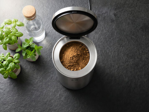 Modern electric countertop composter turning food scraps into organic fertilizer powder in a kitchen setting.