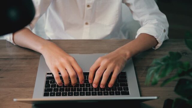 High angle close-up view of male hands typing on a laptop keyboard. Unrecognizable businessman or freelancer working on a computer, coding, or sending emails from his office desk