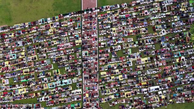 Aerial view of a large crowd of people praying on colorful mats in an outdoor grassy field Klaten, Jawa Tengah, Indonesia.