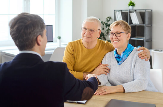 Senior couple meeting advisor for retirement planning. They agree after consultation on finance and insurance, shaking hands to confirm trust. Concept of guided financial decision making.