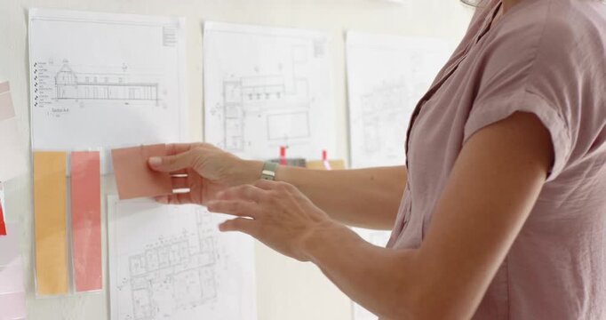 Woman placing pink swatch spotting match pinup layering strips finishing scheme, copy space