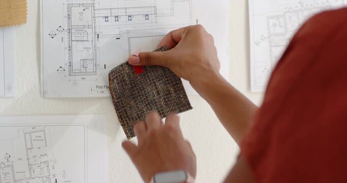 Female designer in rust top bringing swatch, aligning, taping red tape on plan testing, copy space