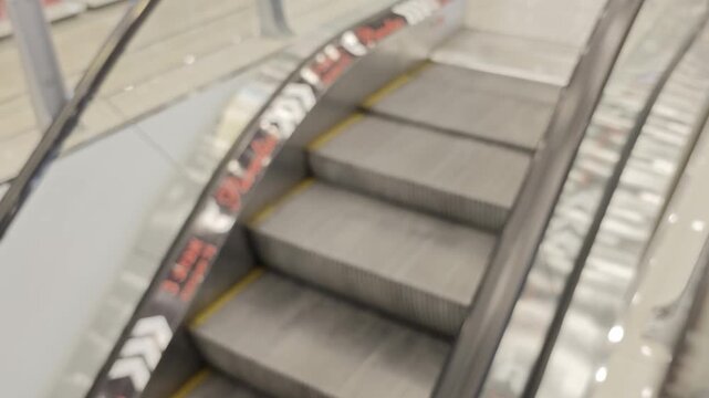 View of stairs and escalator in a busy shopping mall during the day