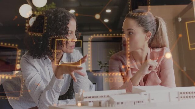 Two designers starting review, left gesturing, right pointing, orange HUD marking model, deciding