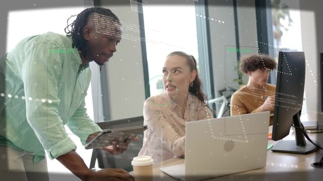 Standing coworker leaning and pointing at laptop while holding tablet guiding peer for design check
