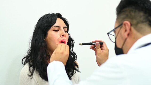 1080p 60fps horizontal video of a doctor examining a patient's throat with his tongue depressor, both of Latin origin
