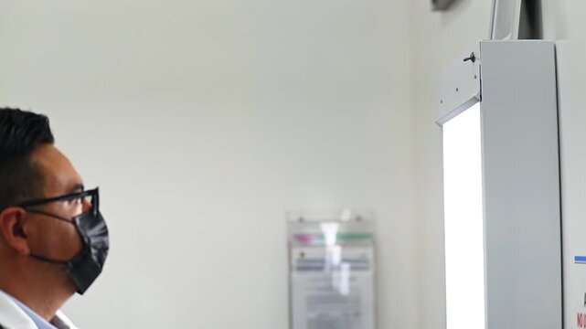 1080p video at 60 fps horizontal of a doctor turning on his negatoscope to review x-rays at a medical appointment
