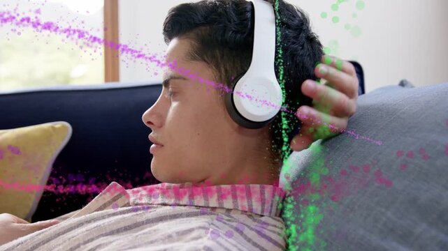 Vertical video: Leaning back striped shirt man settling on sofa, fixing white headset and singing