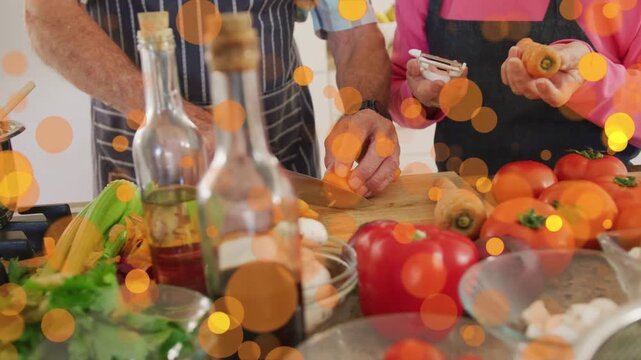 Camera shifting focus, man slicing carrots, woman peeling, orange bokeh guiding meal prep