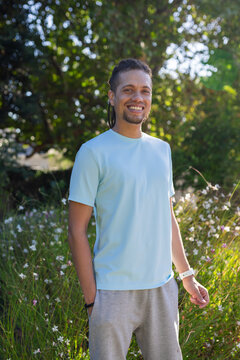 African American man standing in park wearing light blue tee gray sweats showing watch, bracelet