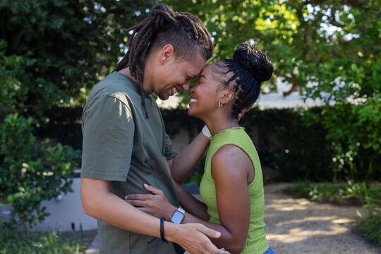 Couple standing with foreheads touching, holding torso in backyard, wearing olive tee and lime top