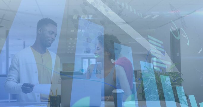 Discussing coworkers in office attire at modern workspace leaning toward laptop, showing charts