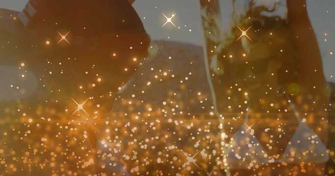 Leaning pair adults interacting on hillside at sunset, showing beanie, hoodie, green garment, bokeh