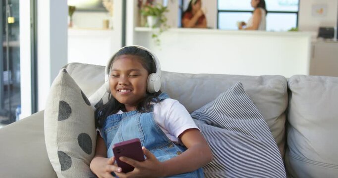 African American child on sofa near window headphones on singing tapping purple phone women talking