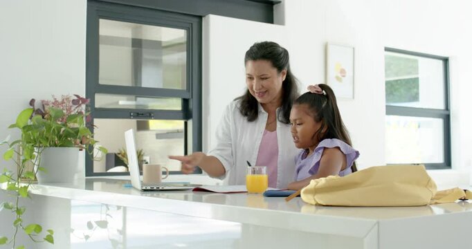 African American mother and youth daughter starting homework by placing laptop and opening notebook