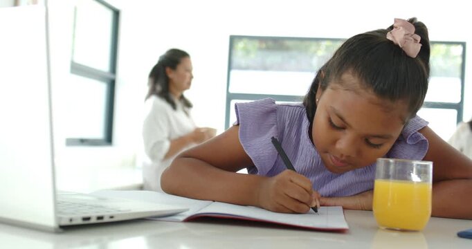 African American mom and child watching child doing homework in notebook pencil mom coming guiding