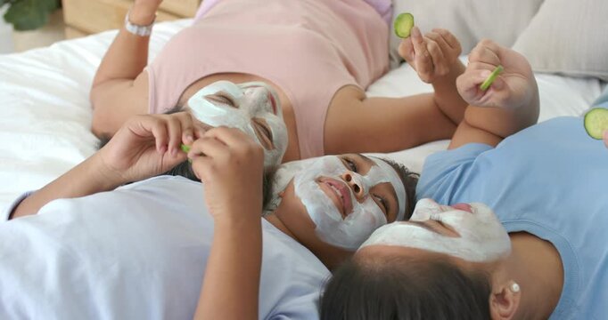 Diverse family laughing while raising cucumber slices, placing them over eyes on bed with masks