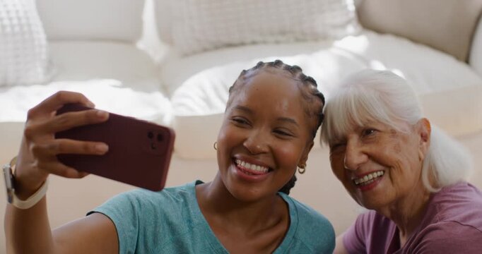 Female family, Senior woman and woman raising maroon phone taking selfie capturing memory on sofa