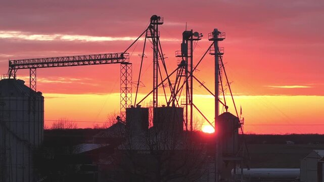 Aerial view of industrial grain elevators and silos silhouetted against a vibrant red sunset sky in Wilmington, Ohio, United States.
