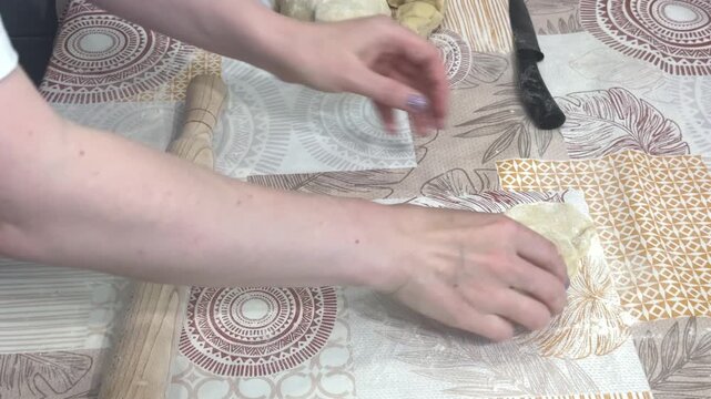 A woman uses a wooden rolling pin to flatten dough for traditional homemade dumplings in a bright kitchen, cozy home atmosphere, cooking hobby, family meal prep.