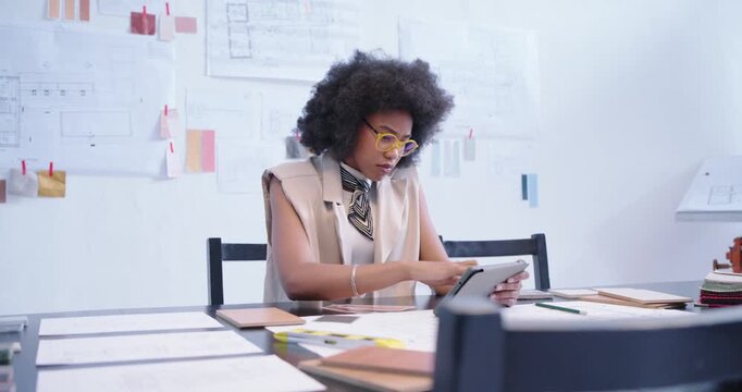 African woman using tablet drawing plan with yellow pencil aligning swatch editing layout at studio