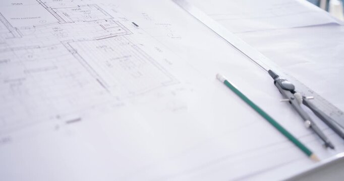 Camera is panning right, moving closer to show pencil and compass on blueprint by window