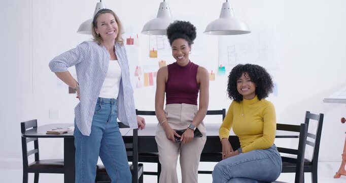 Diverse female colleagues gathering at high table, center woman holding tablet, sparking laughter
