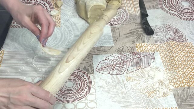 A woman carefully flattens dough pieces with a rolling pin and shows the finished thin circle to the camera, cooking masterclass, homemade recipe, culinary skills.