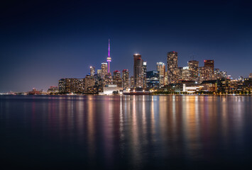 Naklejka premium Illuminated Toronto city skyline at night on Lake Ontario - Toronto, Ontario, Canada