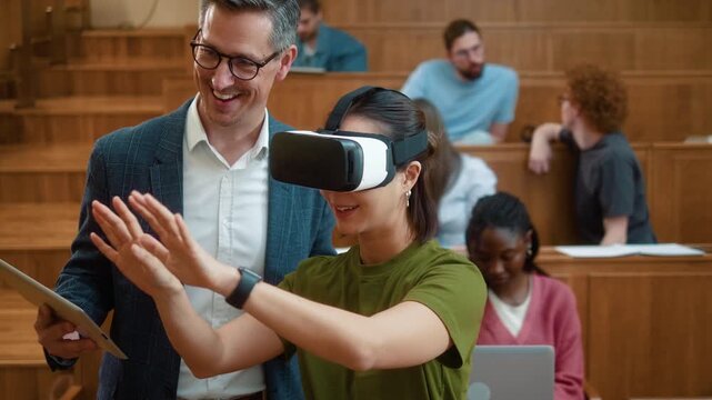 Professor with digital tablet guiding Korean female student using VR headset during university class. Diverse students observe immersive learning experience with laptop and modern education technology