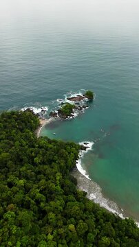 Aerial view of Bahia Solano with lush tropical forest meeting the turquoise ocean and rocky islets in Mutis, Choco, Colombia.